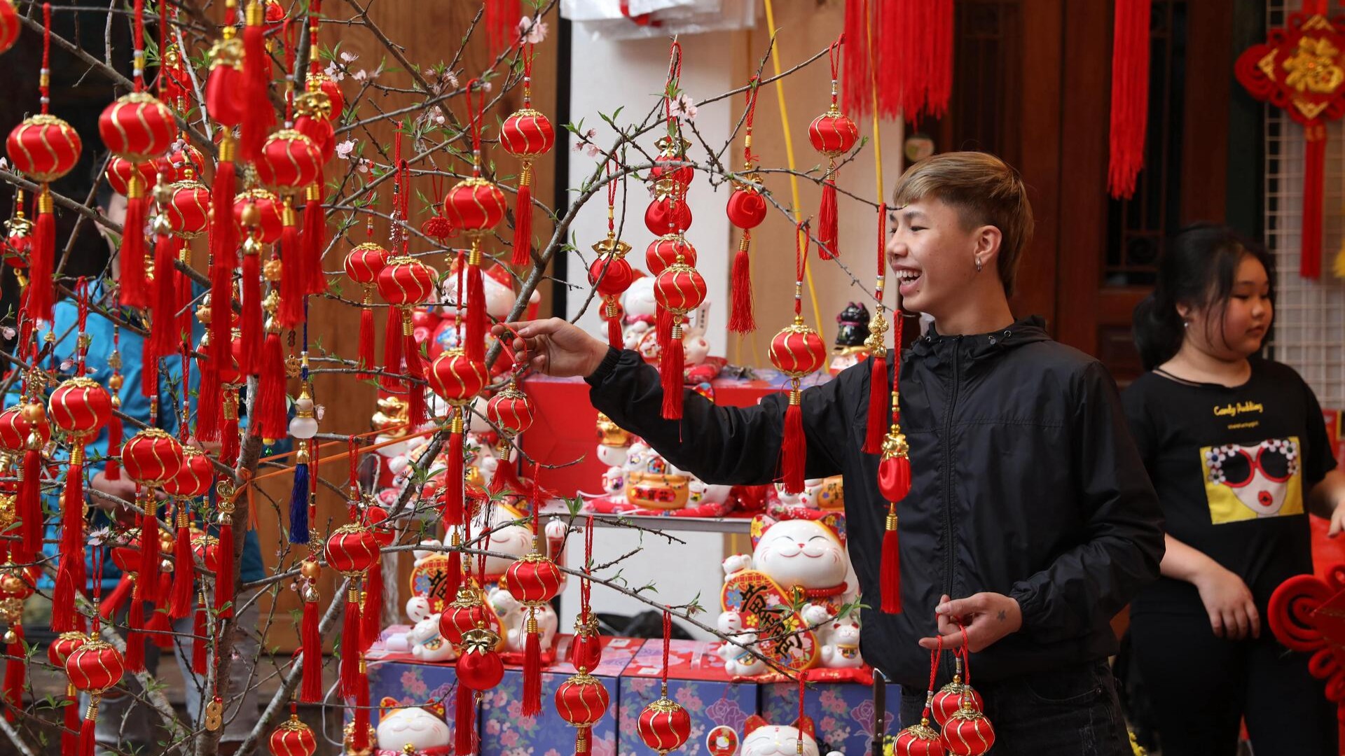 Мужчина развешивает красные фонарики на ветвях деревьев в Ханое перед праздником Тет Нгуен Дан.