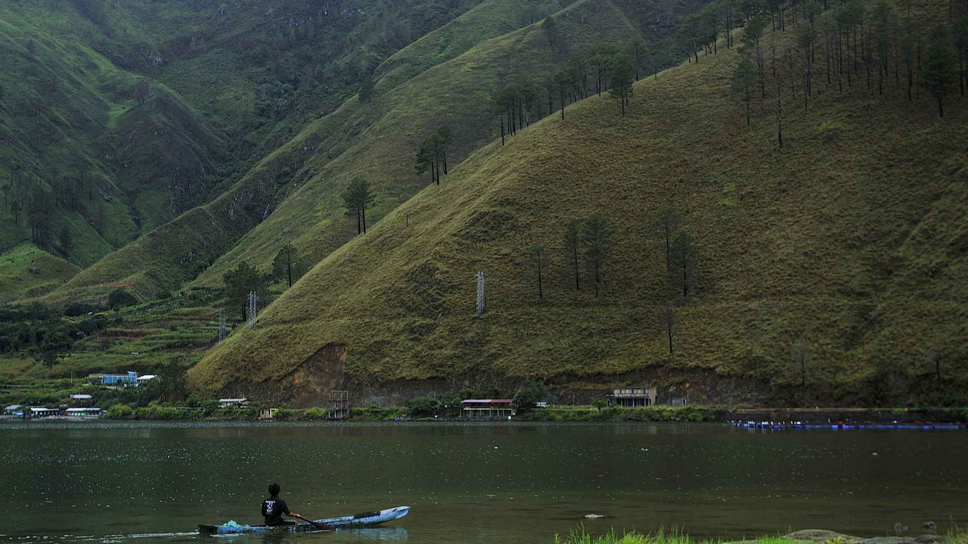 Мужчина плывет на лодке по озеру Тоба в Северной Суматре, Индонезия.