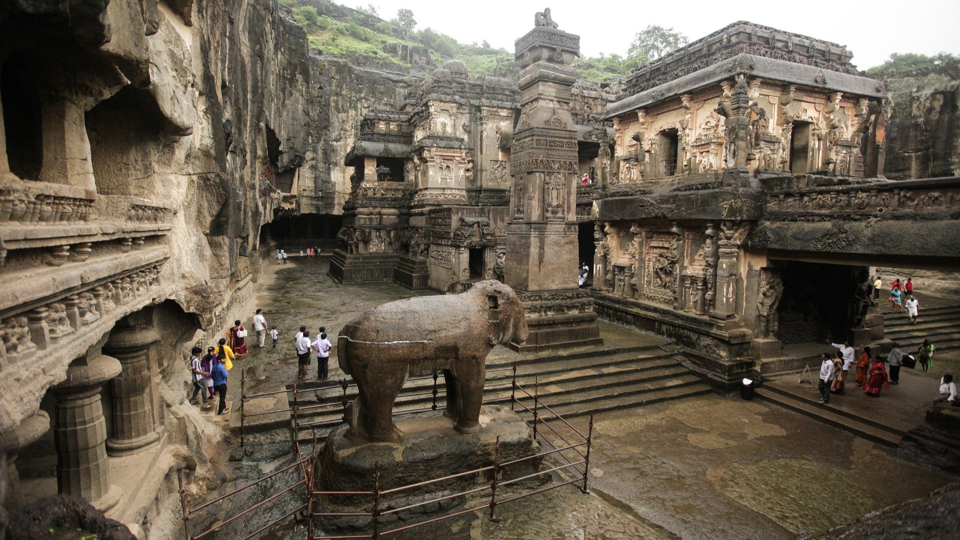 Туристы посещают каменный джайнский храм в пещерах Эллора.