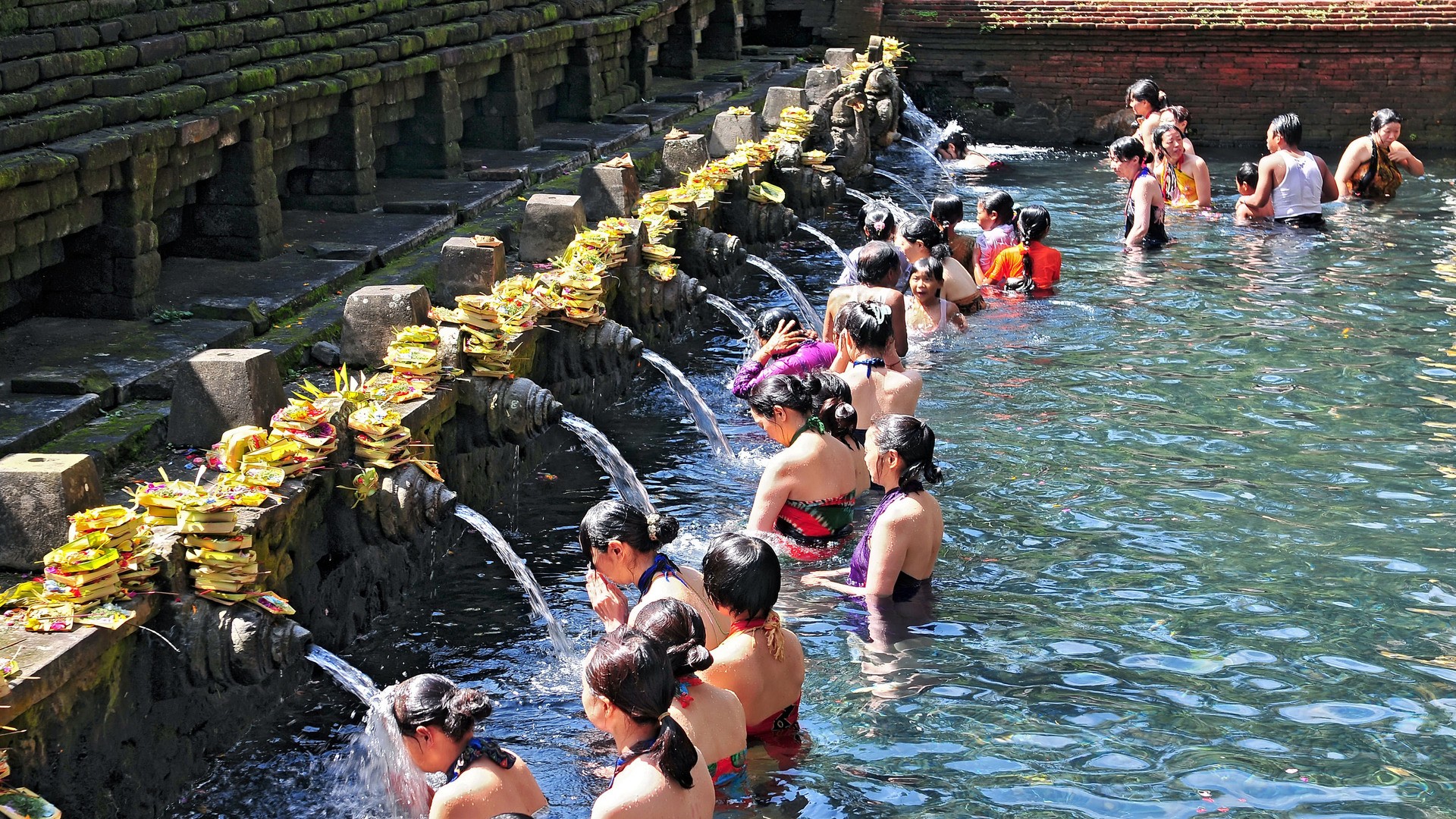 Cемьи приезжают к священным источникам Тирта Эмпул на Бали.